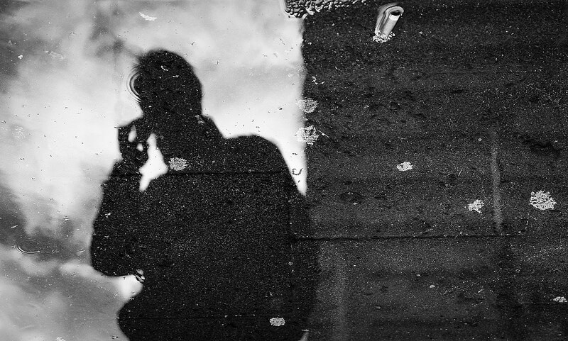 reflection in a puddle of a person calling