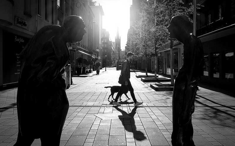 man walking his dog seen between statues