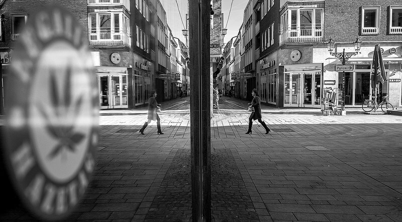woman walking on the street with her reflection in a window
