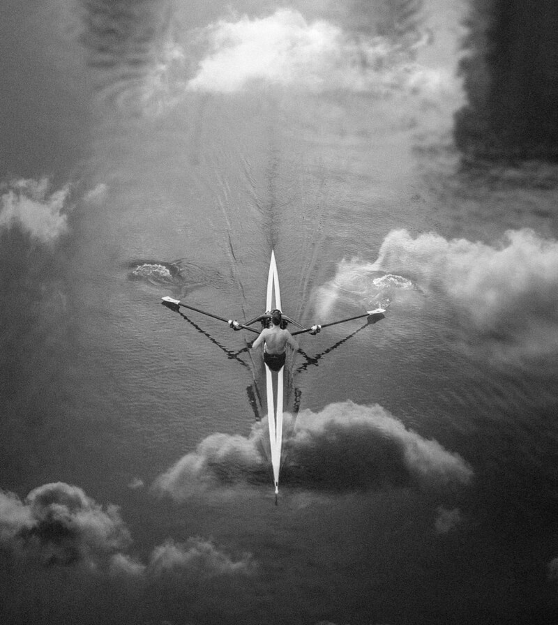 man rowing in Düsseldorf Media Harbor with reflections of clouds