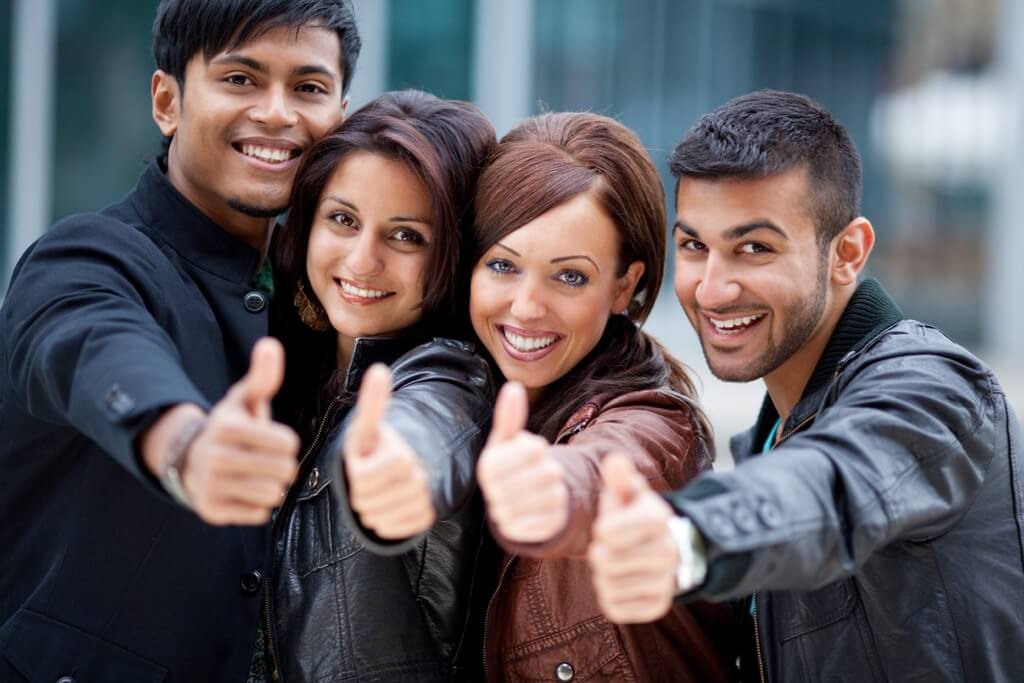 Four friends giving a thumbs up