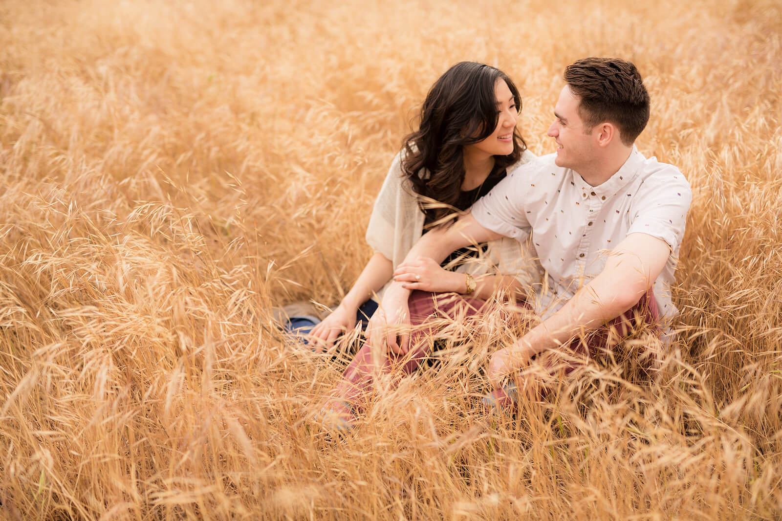 couple sits in field under overcast sky as best time to take photos outside
